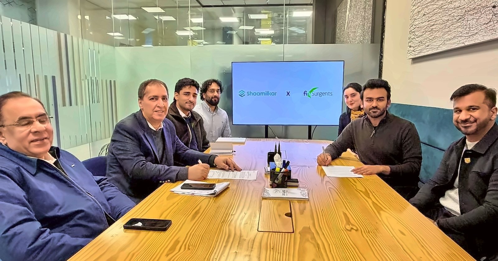Finsurgents and Shaamilkar teams signing their partnership agreement around a conference table